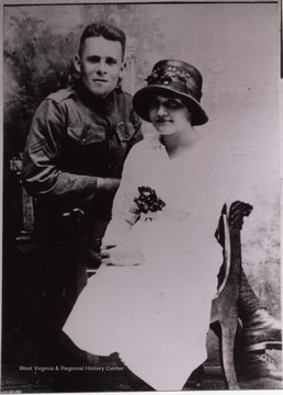 Couple posed for a formal portrait. The woman is wearing a hat.