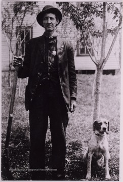 Man in a uniform posed with a dog.