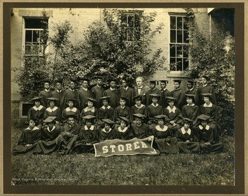 Group photo of Storer College class of 1932 in caps and gowns in front of building with "STORER" banner. College President McDonald in back row.