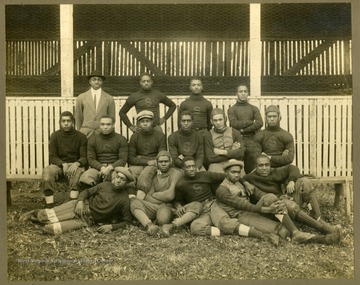 Storer College football team in uniform in front of dugouts.