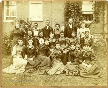 Group photo of Storer College students in front of building. Two people looking out window on right.