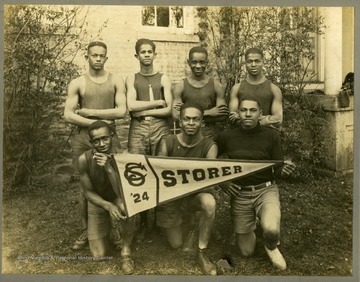 Storer College Track team in uniform by building.