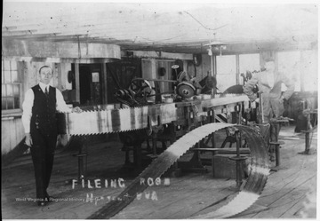 The blades in the foreground and on the filing machine are for a double cut band saw, while the one suspended from the ceiling is for a single cut rig.