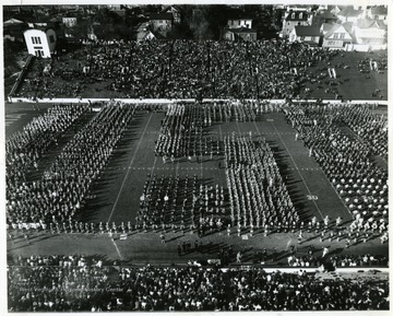 Band Day halftime field show at the WVU-Kentucky game. "Forty four high school bands from West Virginia and nearby Pennsylvania, some 3000 bandsmen came together on Mountaineer Field for the 1964 Band Day Show."