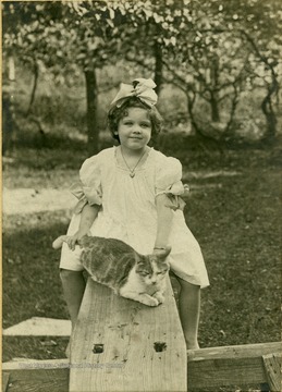 Frances D. Packette and her pet cat, Schley-Puss, on a see-saw.