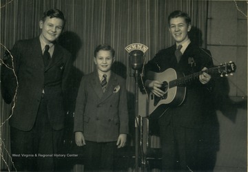 West Virginia Country and Western performers, The Franklin Brothers, left to right, Billy, Delmos and Clyde, standing behind a microphone at radio station, WMMN in Fairmont, West Virginia.