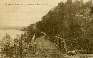 Postcard photograph of River Road along the Potomac River at Shepherdstown. The structure in the background is probably Boteler's Cement Mill and site of the Battle of Shepherdstown, September 20, 1862, following the Battle of Antietam during the Civil War.  