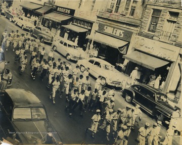 Little League teams parade down High Street past Rogers' Jewelry Store,and Sidler's Department Store. 