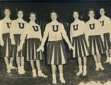 Group portrait of unidentified members of the University High School Cheerleaders in uniform, photograph taken at night.