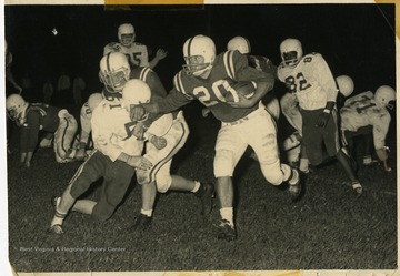 Monty Shear, #20 of the Morgantown High Mohigans, gains yardage in a night game.