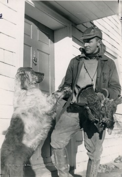 Author, hunter and artist, George Bird Evans holds his kill and the paw of his English Setter.