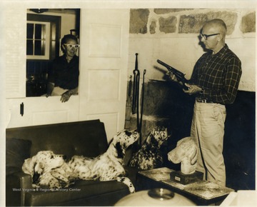 George Evans displays a revolver to his wife Kay and three blue belton setters.  