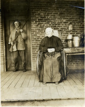 Albert Price holding an old muzzle loading musket and his sister (in-law?) is seated in a wheelchair.