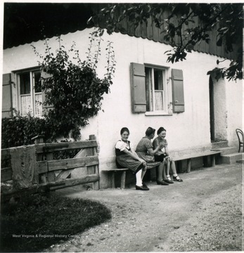 Three unidentified women chat outside a dwelling in the Bavarian Alps, Germany