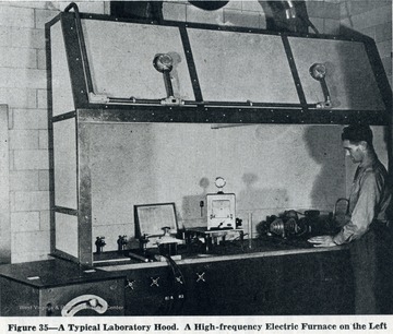 Unidentified man stands next to lab hood.