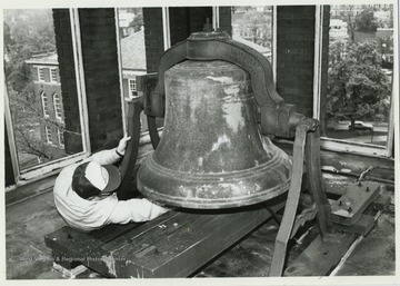 Unidentified worker stretches to keep the Woodburn Hall bell chiming in tune.