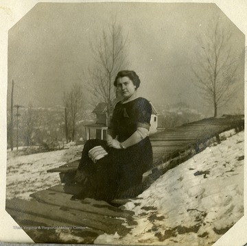 Anna Mathers poses on the boardwalk outside her house, surrounded by snow covered ground.