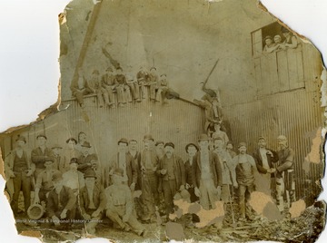 Unidentified workers, men and boys pose outside, probably a factory/or mill.