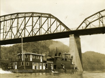 The ship "Dwight F. Davis" sails under a bridge. This ship was built by The Charles Ward Engineering Works in Charleston, West Virginia.