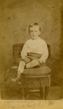 A carte de visite of a young boy posed on a fringe trimmed chair.