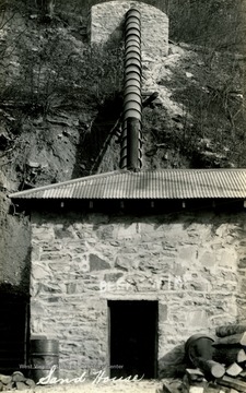A stone sand house where sand was stored, has a large pipe connection up the mountain. 