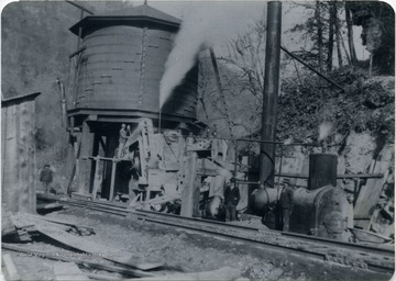 The man standing beside the steam boiler is J. A. Coulter, who later became an engineer for C&amp;O, others in the photograph are not identified. The water tank is the original, it was replaced several years later by another. This photograph was taken before the double track was made through Sewell. Other information on the back of the photograph includes: " C to Ry Engineer deceased via Jim Henry Waverly - C. A. Coulter 209 First Street, West Logan, W. Va. 25601".