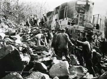 Unidentified men work to salvage the wrecked train in Fayette County. Other information on the back of the photograph includes, "Hinton Daily News Coll from Fred Long to Stephen D. Trail, Su Co WV 8-26-1996".