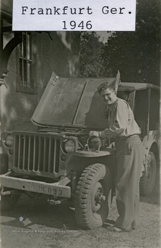 Corporal Carpenter checks under the hood of a jeep in Post World War II, Frankfurt, Germany.