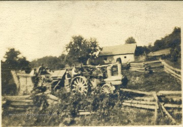 Image of a steam engine, wood fired tractor rolling in front of J. Z. Ellison's sheep barn.