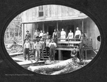 Unidentified people gathered in front of a two-story house for this photograph.