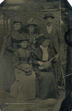 Four unidentified women and one man pose for this tintype as one woman strums a banjo.