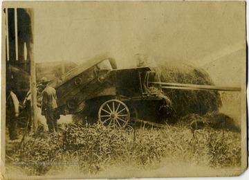 Information included with the photograph, unidentified workers were "... probably thrashing clover for seed ... Note the wooden wheels on the thrashing machine."