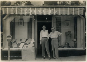 The description in the album labels the building as "The House of Chevey". On the left is Mathers "Mike" Barrick and on the right is an unidentified employee. 