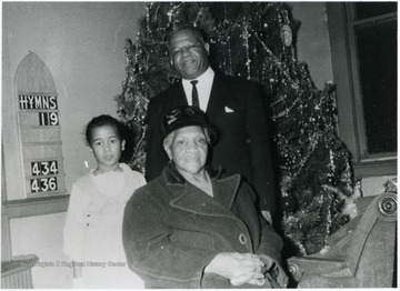 Karen Ward (far left), Mary Ward (center) and Jack Ward Sr. (back). This photograph was taken at Mt. Herman Baptist Church. It replaced St. Paul's African Methodist Episcopal (AME) Church in 1991 after it was torn down. Information on p. 131, 163 in "Our Monongalia" by Connie Park Rice. Information with the photograph includes "Courtesy of Jack Ward Jr.".