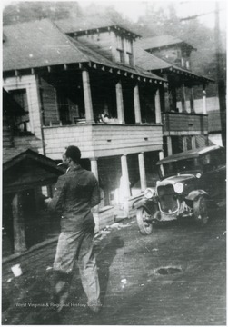 Lawrence Jackson with a cigarette, standing in front of several neighborhood houses. Information with the photograph includes "Courtesy of Bobbie Drew Ward".