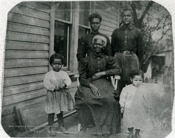 The woman seated in the photograph is Prisilla or "Aunt Prissy". She was a slave in the before the Civil War and owned by the Dorsey family of Morgantown. All others are unidentified. Information on p. 22 in "Our Monongalia" by Connie Park Rice. Information with the photograph includes "Reproduced from Spinster Photo Book Club, duplicate held by WVU Women's Centenary Project, Center for Women's Study Archive. Original loaned by Ruth Lawrence Mahaney."