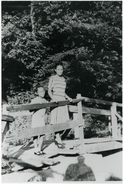 Two African-American girls pose on a foot-bridge. Information on p. 149 in "Our Monongalia" by Connie Park Rice. Information with the photograph includes "Courtesy of Bobbie Drew Ward."   