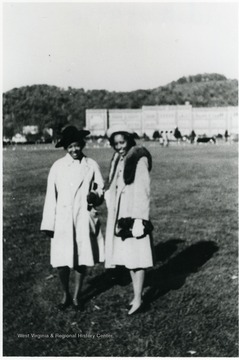 Ivry Williams and unidentified woman pose in front of a campus building at West Virginia State College. The college is located in Institute, Kanawha County. All other persons in the photograph are unidentified. Information on p. 130 in "Our Monongalia" by Connie Park Rice. Information with the photograph includes "Courtesy of Ivry Moore Williams."   