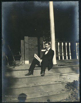 An unidentified WVU student reading on the front steps of the dormitory. Episcopal Hall was established by the West Virginia Diocese ca.1895, primarily to house and feed WVU men who planned to become candidates for the Episcopalian ministry.