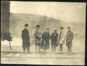 Several well-dressed young men stand on the track next to a Baltimore and Ohio Railroad Car. The Baltimore and Ohio Railroad Company was one of the oldest railroads in the U.S. It passed through Maryland, West Virginia, Virginia and Ohio. The men are probably West Virginia University students headed out of Morgantown.