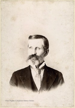 Cabinet card portrait of an older man with a beard wearing a suit and tie. 