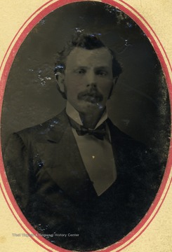 A young man with a mustache,dressed in a suit and bow tie. 