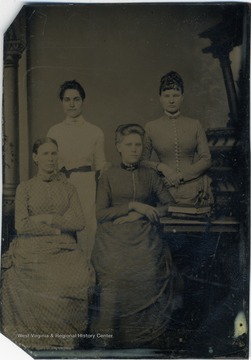 Four young women all wearing long, high collared dresses. 