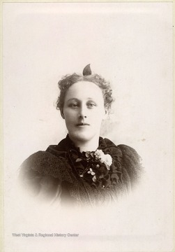 A young woman wearing a long, ruffled, black dress. Large mounted prints such as this are called cabinet cards. 