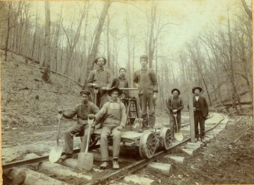 Workers pose on a hand car and railroad track. Jesse C. Simms, 2nd from right. All other persons in this photograph are unidentified. 