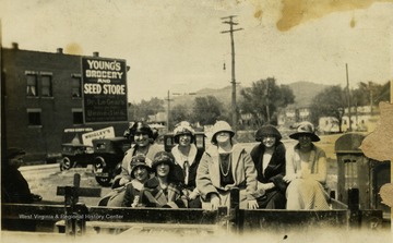 Group portrait of unidentified women, smartly dressed, seated in the bed of a pick-up.