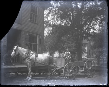 Two unidentified boys sit in a hitched wagon outside the store.