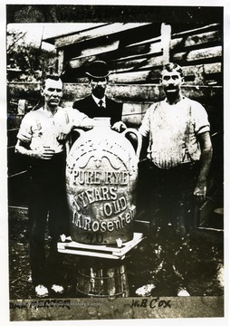 Dan Mercer, Walter Donnaghho and W.B. Cox. stand with large jug. The name on the jug, "L. A. Rosenheim" was one of the pioneer salon keepers in Parkersburg. 