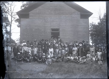 Unidentified large group of people, several sitting in the first row holding guitars, pose for the photograph.