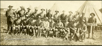 Group portrait with camp tents in the background, none of the men are identified